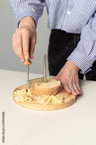 Round cheese knife. Tete de Moine. Woman cuts cheese. Girolle cheese knife. Slicing for serving
