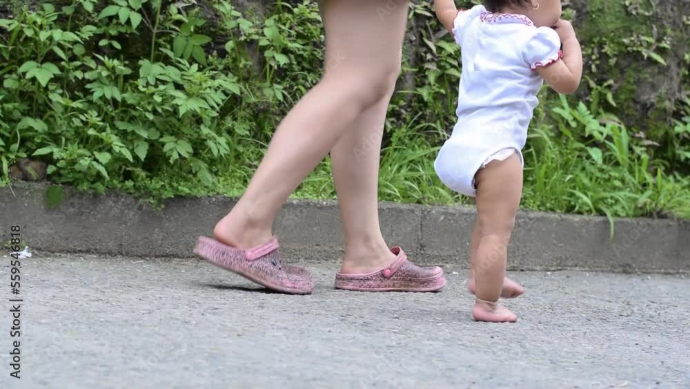 close-up of a mother's feet walking with her baby in the street, going for a walk so that the little baby learns to walk close-up of a mother's feet walking with her baby in the street, going for a walk so that the little baby learns to walk