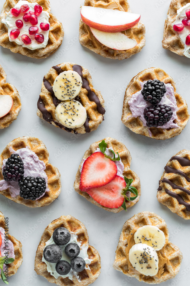 Mini heart shaped waffles with various toppings of spreads and fruit.