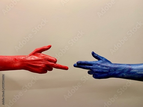 Dwie dłonie w kolorach czerwonym i niebieskim na jasnym tle. Język dłoni, układ palców, kolorowe ręce na jasnym