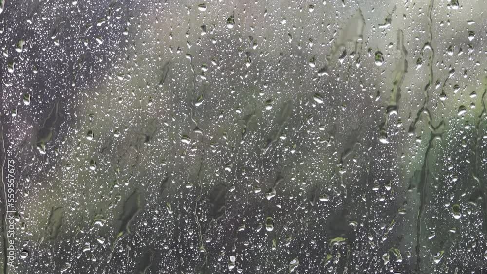 Rainy weather behind the glass of a wet window with falling drops of heavy rain. Rainy weather behind the glass of a wet window with falling drops of heavy rain.