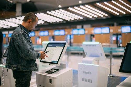 Obraz na plátně A male passenger at the electronic check-in desk in the departure area of the modern airport terminal