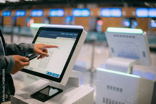 A male passenger at the electronic check-in desk in the departure area of the modern airport terminal.