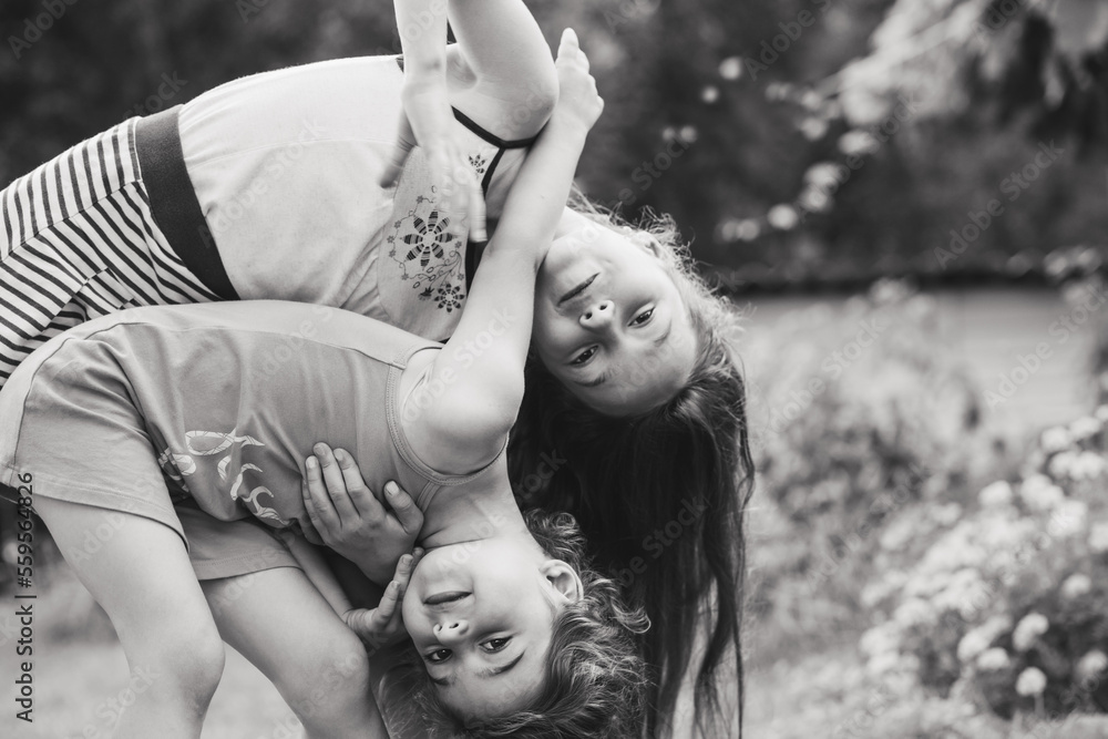 Black and white Portrait of Two Cute little girls embracing and laughing at garden. Happy kids outdoors Black and white Portrait of Two Cute little girls embracing and laughing at garden. Happy kids outdoors