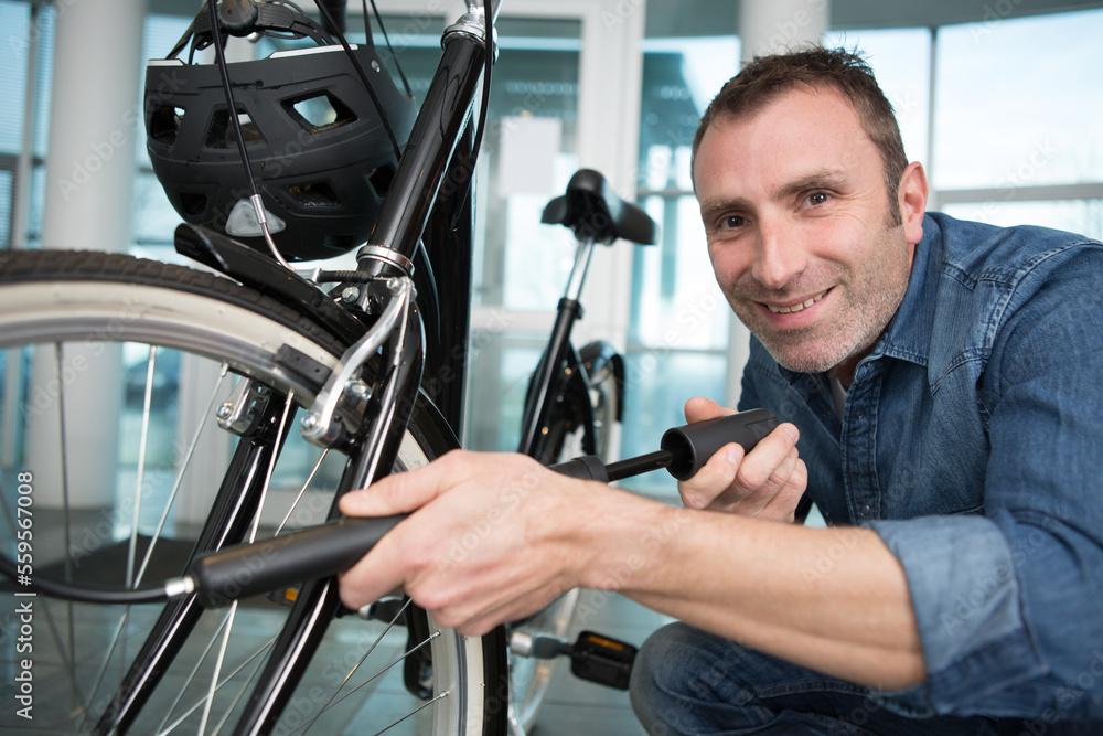man pumping up his bicycle tyre indoors man pumping up his bicycle tyre indoors