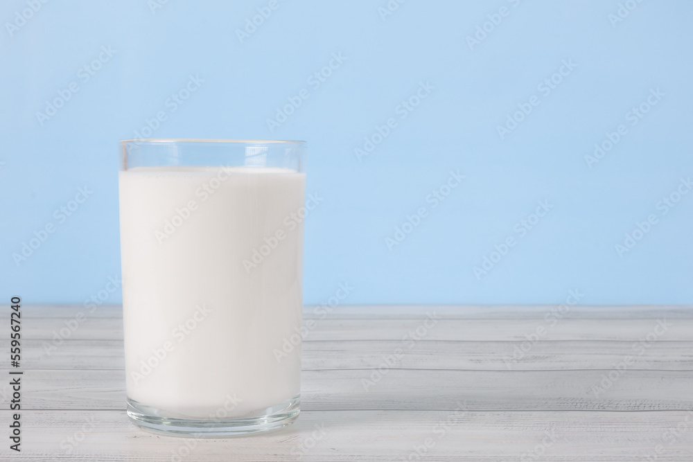 The glass full of milk on wooden table. Glass of fresh white milk on blue background in the kitchen. The glass full of milk on wooden table. Glass of fresh white milk on blue background in the kitchen.