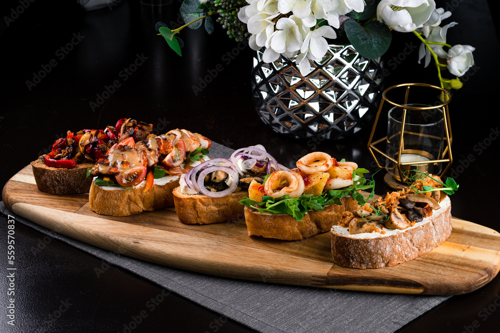 Set Italian snacks bruschetta with seafood, meat and vegetables on a wooden board.