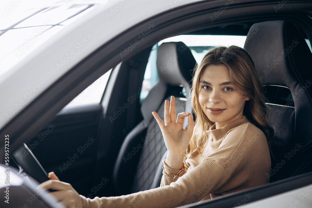 Woman sitting in her new car in car showroom