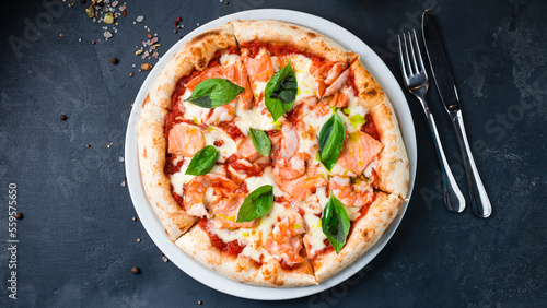 Pizza with shrimp, salmon, mozzarella, tomato sauce, basil on a thick dough with spices.