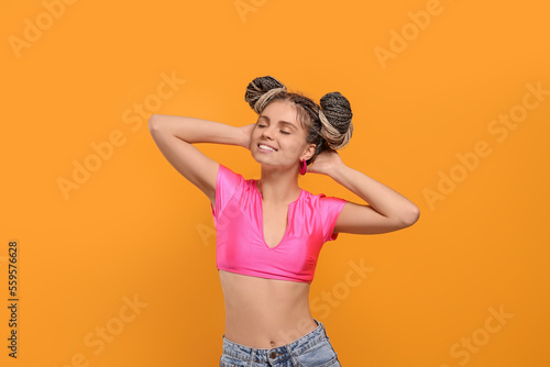 Beautiful woman with braided double buns on yellow background