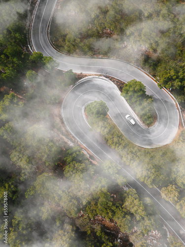 Aerial view of car driving down windy foggy road