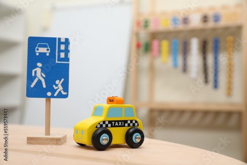 Miniature road sign and car on wooden table, space for text. Montessori toy