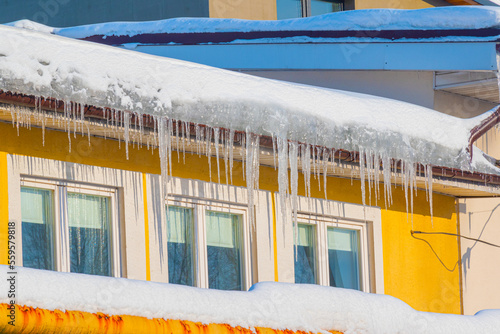 Icicles hanging from the roof of the house on a bright sunny winter day.