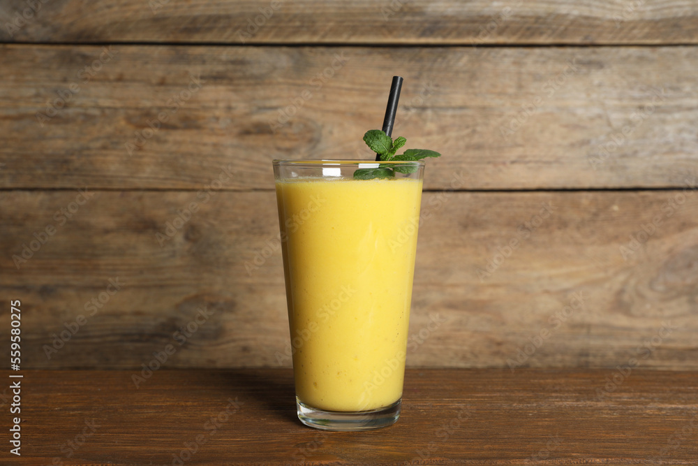Glass of tasty smoothie with straw and mint leaves on wooden table Glass of tasty smoothie with straw and mint leaves on wooden table