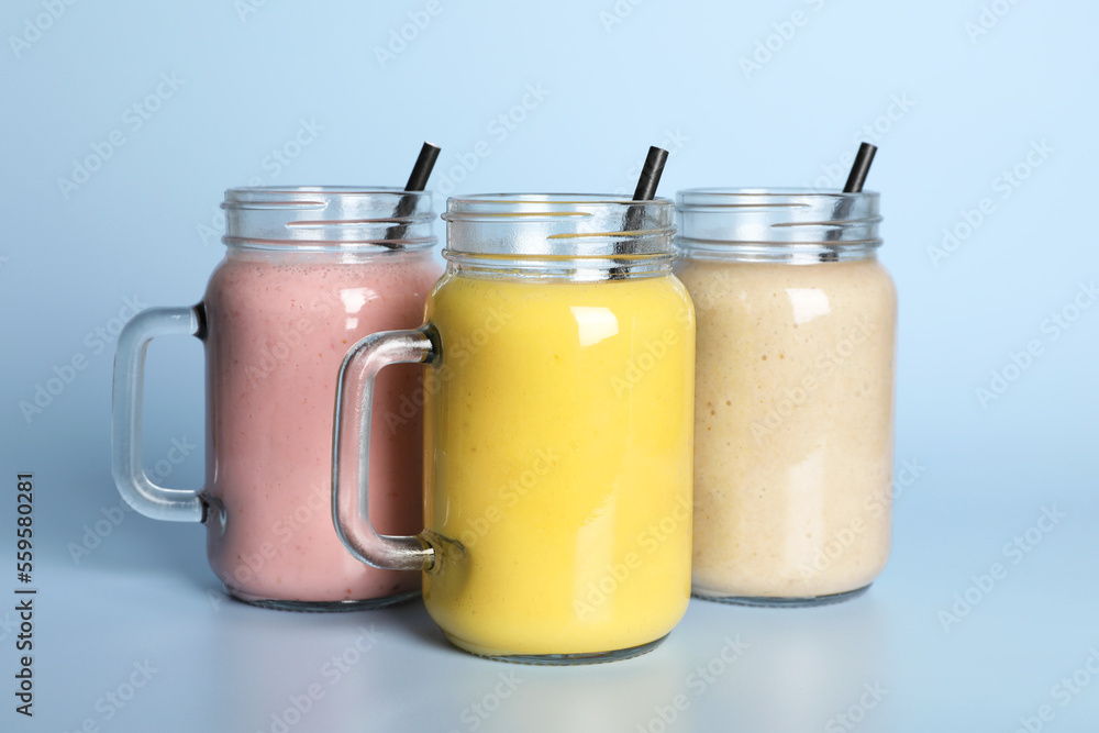 Mason jars with different smoothies on light blue background Mason jars with different smoothies on light blue background