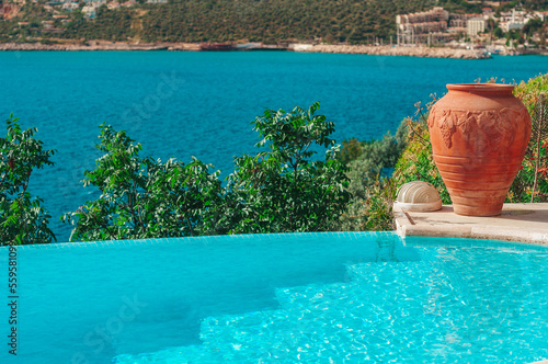 Summer vacation at poolside. Infinity swimming pool with sea on bright summer day