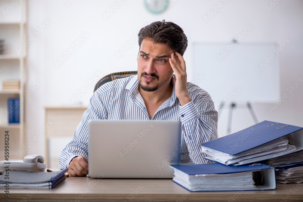 Young male employee and too much work in the office Young male employee and too much work in the office
