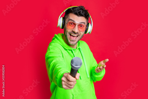 Karaoke DJ isolated on red. Happy man holding mic for singing karaoke songs