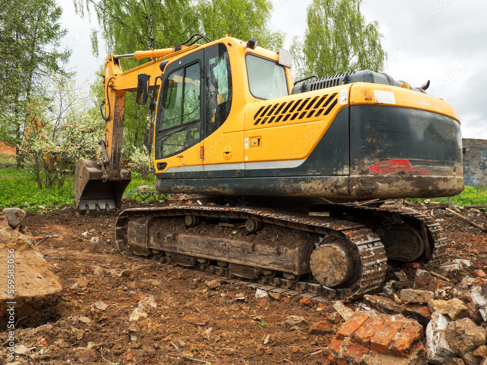 Demolition of a building by an industrial yellow excavator. Demolished broken walls a pile of industrial debris