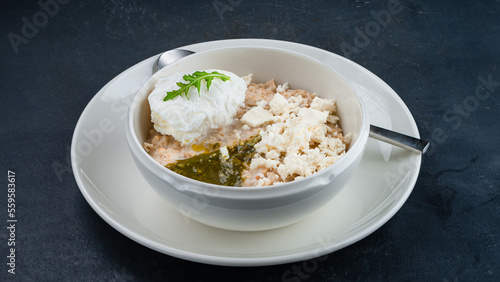 Oatmeal porridge with poached egg, goat cheese and pesto sauce.