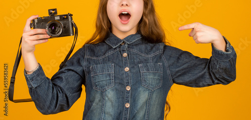 Surprised kid crop view pointing finger at camera yellow background, advert photo