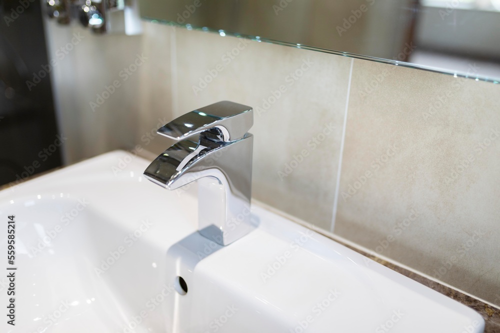 A close up of a shiny chrome modern tap in the bathroom of a luxury hotel A close up of a shiny chrome modern tap in the bathroom of a luxury hotel