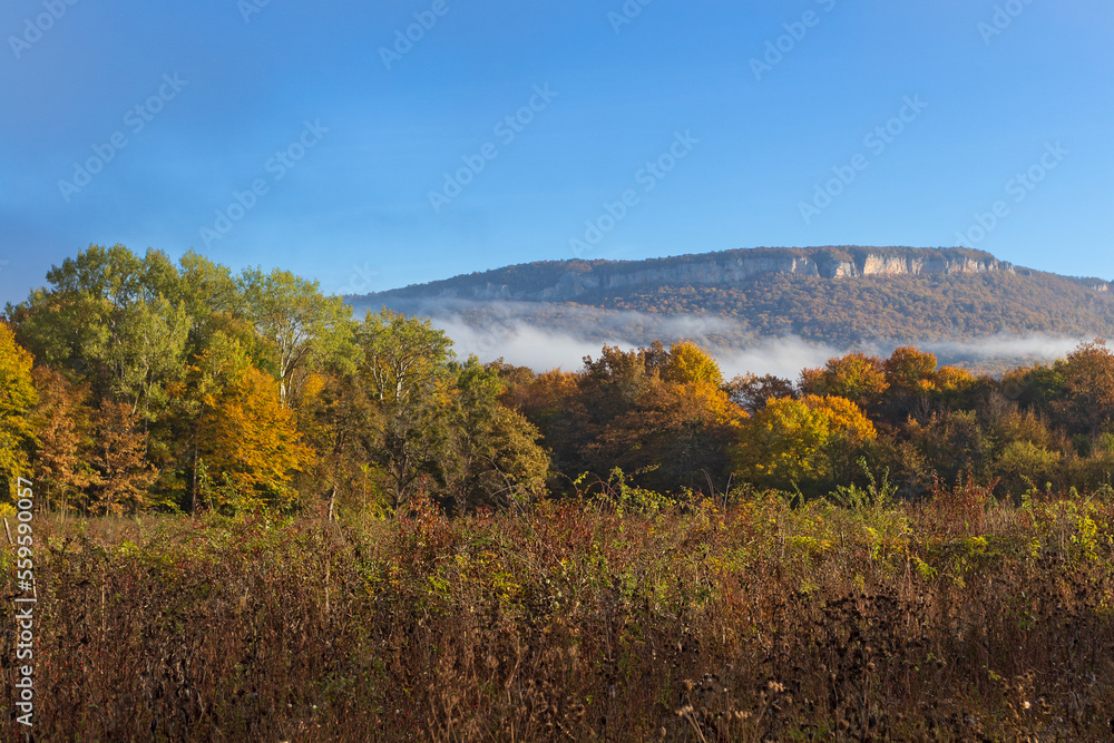 Autumn morning in a mountainous area, a panorama of mountains in a blue haze and the rising sun.
