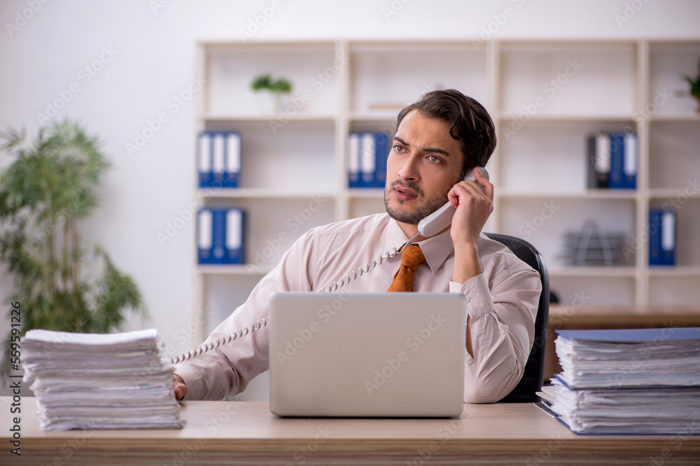 Young male employee and too much work in the office Young male employee and too much work in the office