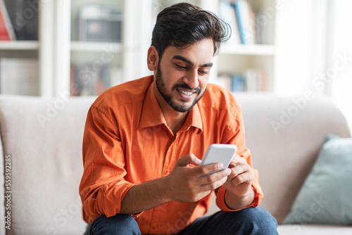 Relaxed cool middle eastern guy using cell phone at home