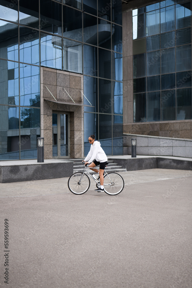African american cyclist in sunglasses and white hoodie riding on street African american cyclist in sunglasses and white hoodie riding on street