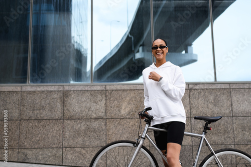 Smiling african american woman in sunglasses standing near bike 
