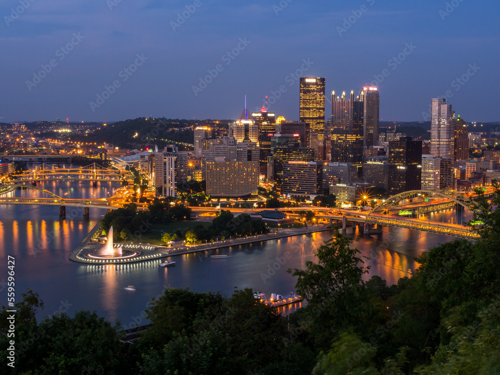 Downtown Pittsburgh skyline at night with rivers, bridges, and the fountain at Point State Park.