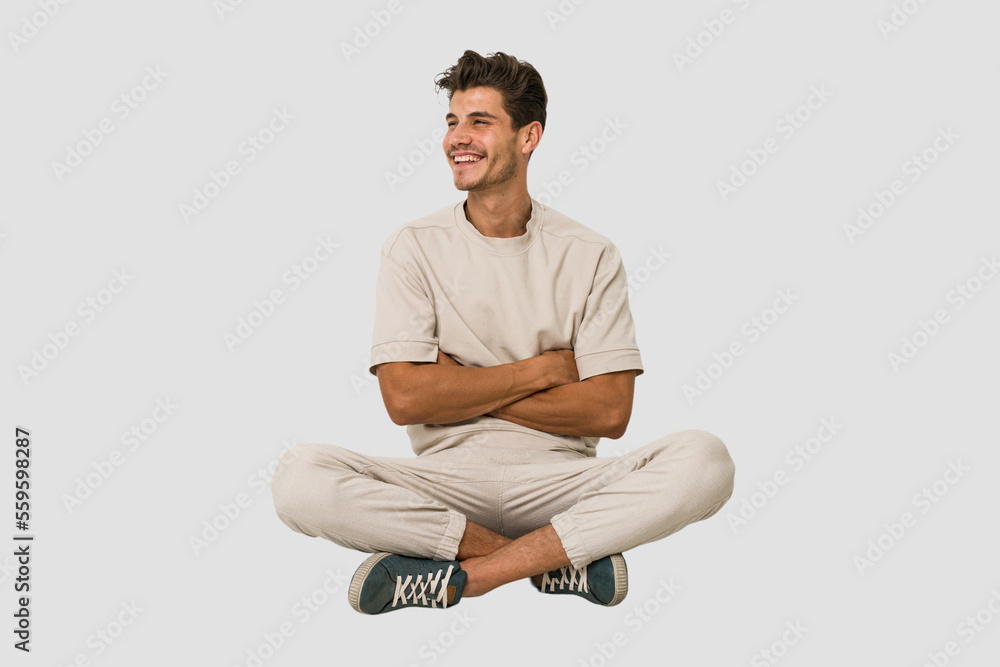 Ταπετσαρία Young caucasian man sitting on the floor isolated on white background smiling confident with crossed arms