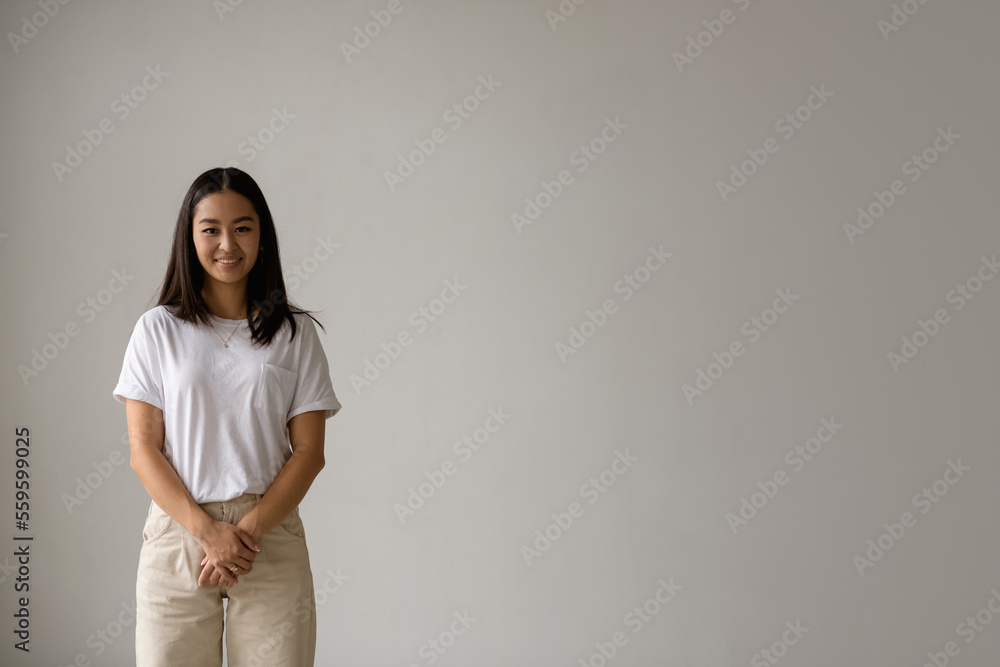 Brunette young asian woman smiling at camera isolated on grey with copy space Brunette young asian woman smiling at camera isolated on grey with copy space