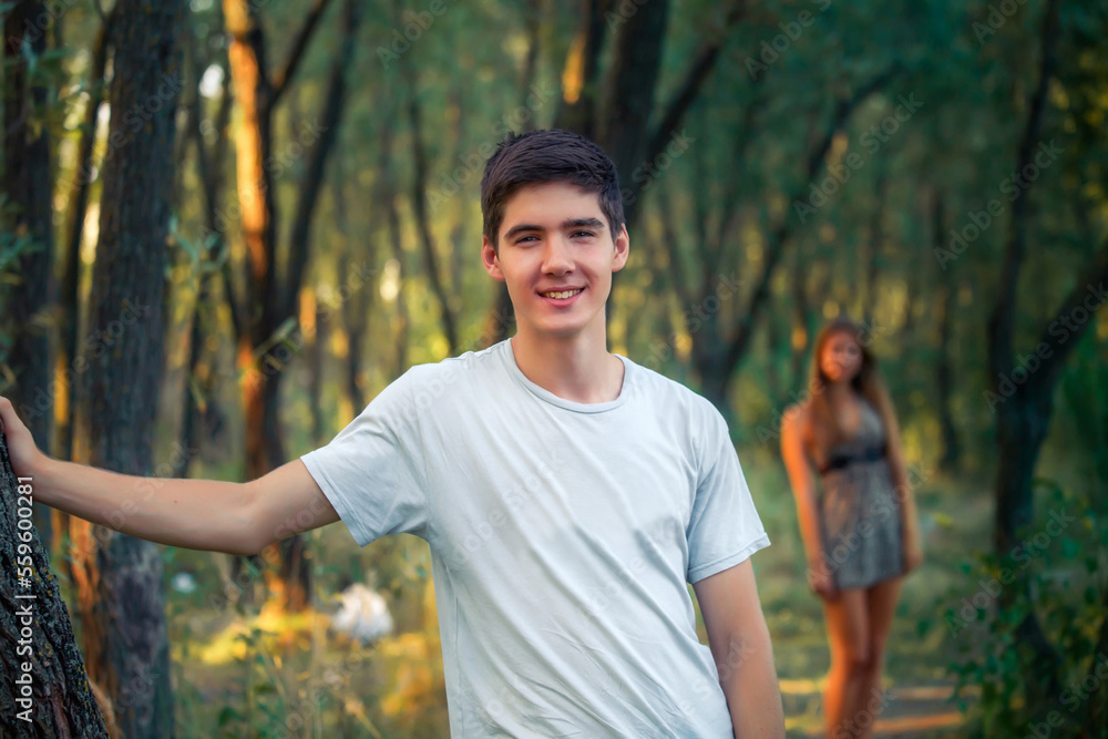 Obraz premium Young guy is based hand on the tree. Distance is girl. In love with a couple