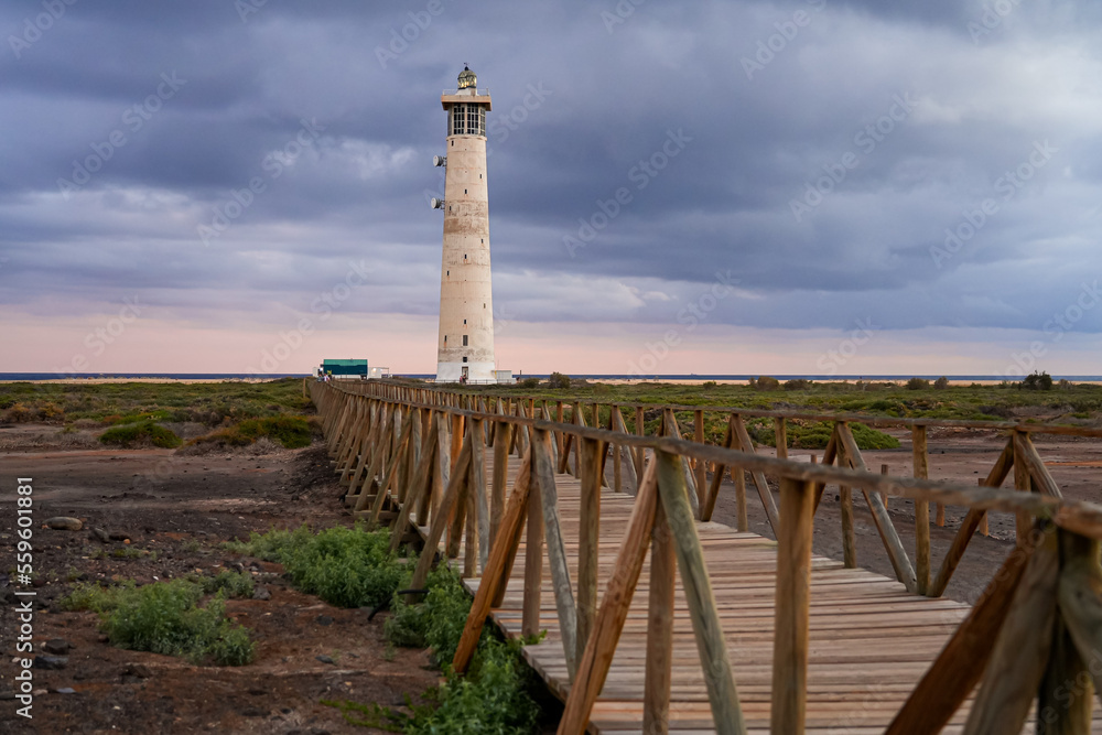 Wooden boardwalk going over marshland towards the Morro Jable lighthouse, built out of concrete in 1991 on the Jandia Peninsula of Fuerteventura in the Canary Islands, Spain