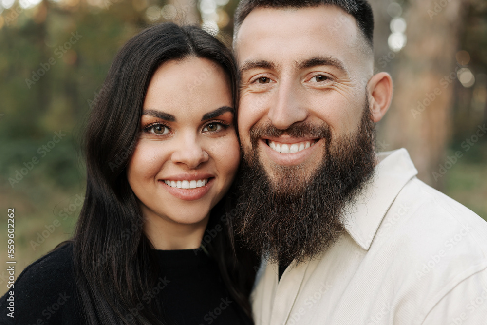 Portrait of happy young woman and man looking in camera enjoy romantic date in park. Smiling bearded man and brunette girl feeling happiness outdoors. Romantic couple enjoying leisure time together. Portrait of happy young woman and man looking in camera enjoy romantic date in park. Smiling bearded man and brunette girl feeling happiness outdoors. Romantic couple enjoying leisure time together.