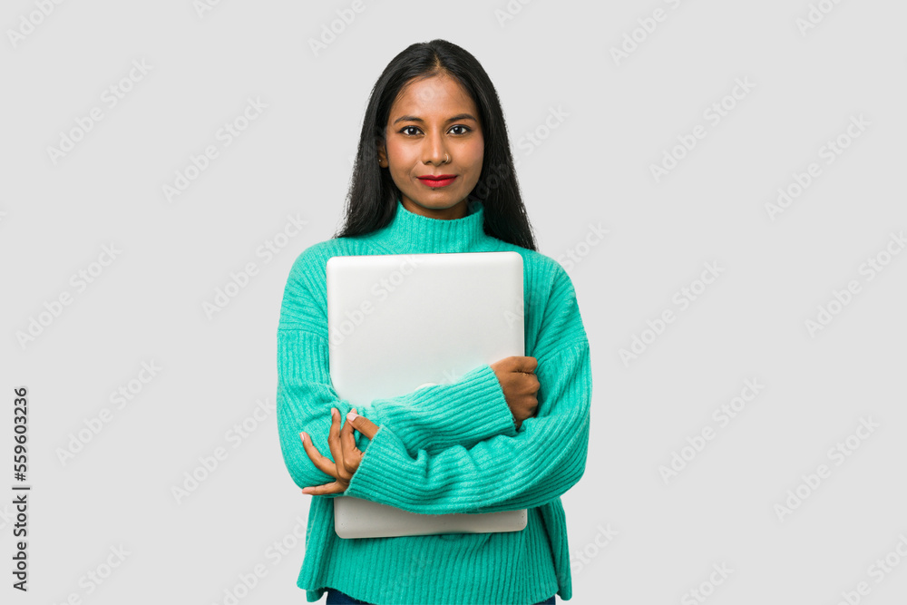 Fototapeta premium Young indian woman holding a laptop isolated on white background