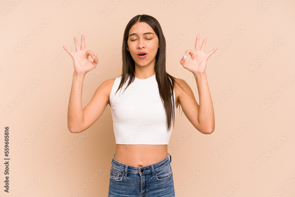 Young colombian woman isolated on beige background relaxes after hard working day, she is performing yoga. Young colombian woman isolated on beige background relaxes after hard working day, she is performing yoga.