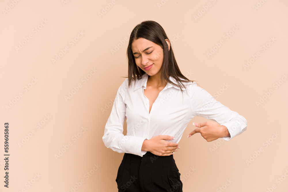 Young colombian woman isolated on beige background having a liver pain, stomach ache. Young colombian woman isolated on beige background having a liver pain, stomach ache.