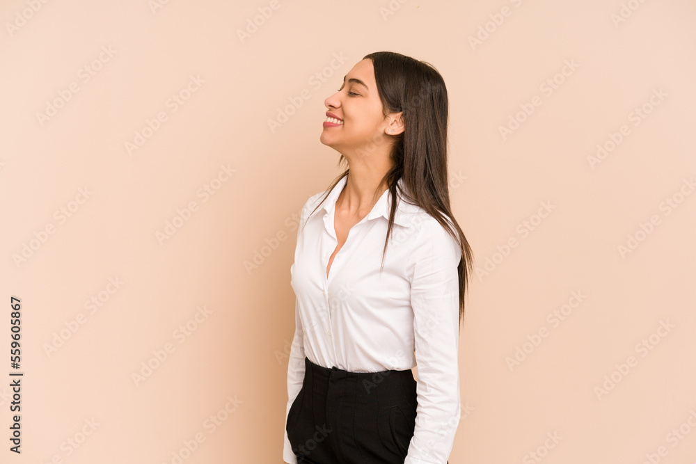 Young colombian woman isolated on beige background relaxed and happy laughing, neck stretched showing teeth. Young colombian woman isolated on beige background relaxed and happy laughing, neck stretched showing teeth.