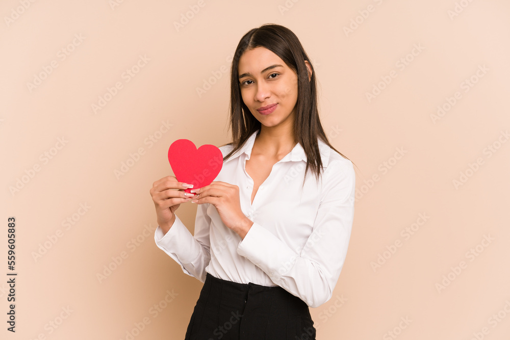 Young colombian woman holding a heart paper for valentines day isolated Young colombian woman holding a heart paper for valentines day isolated