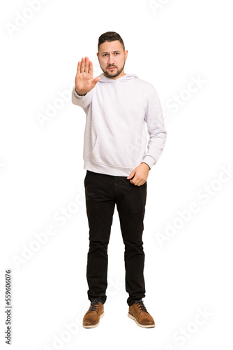 Full body adult latin man cut out isolated standing with outstretched hand showing stop sign, preventing you.