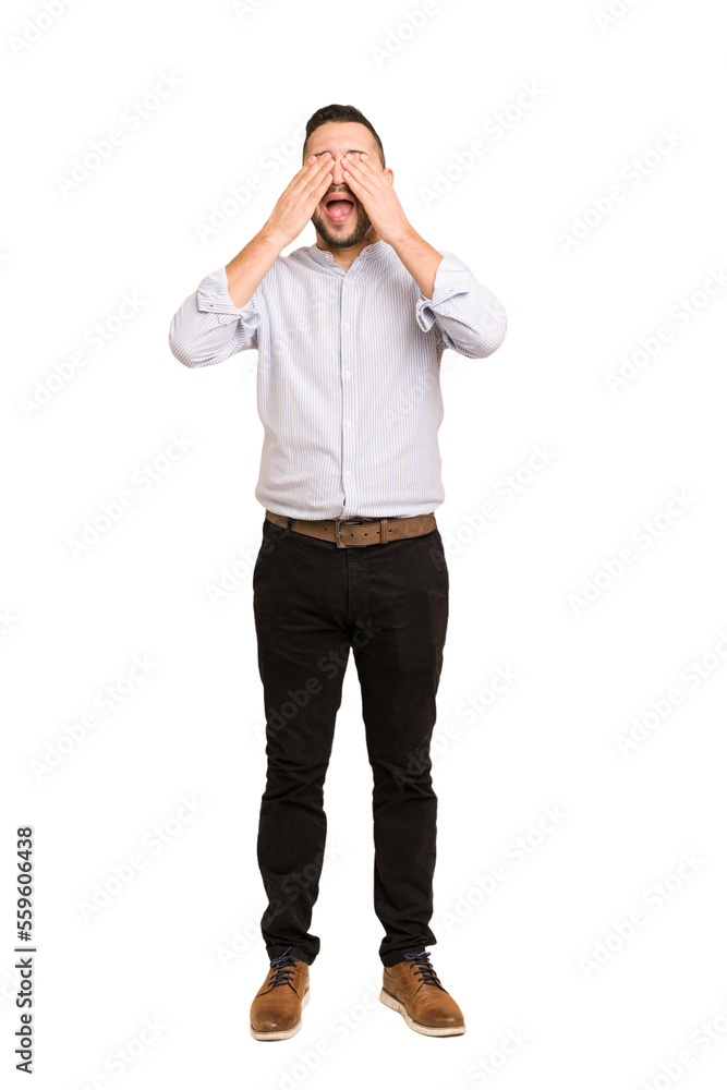 Fototapeta premium Full body adult latin man cut out isolated covers eyes with hands, smiles broadly waiting for a surprise.