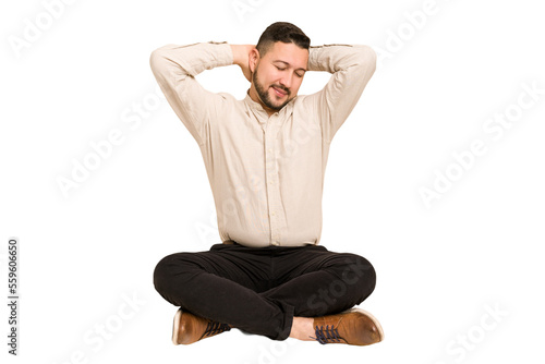 Adult latin man sitting on the floor cut out isolated stretching arms, relaxed position.