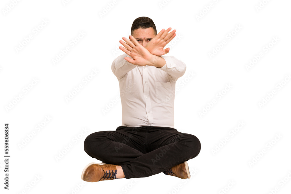 Adult latin man sitting on the floor cut out isolated doing a denial gesture Adult latin man sitting on the floor cut out isolated doing a denial gesture