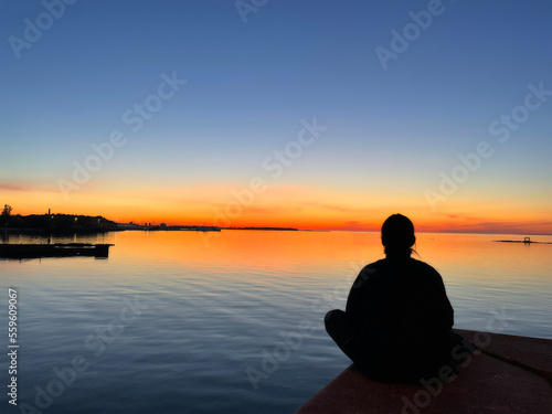 The silhouette of a woman meditating sitting near the sea