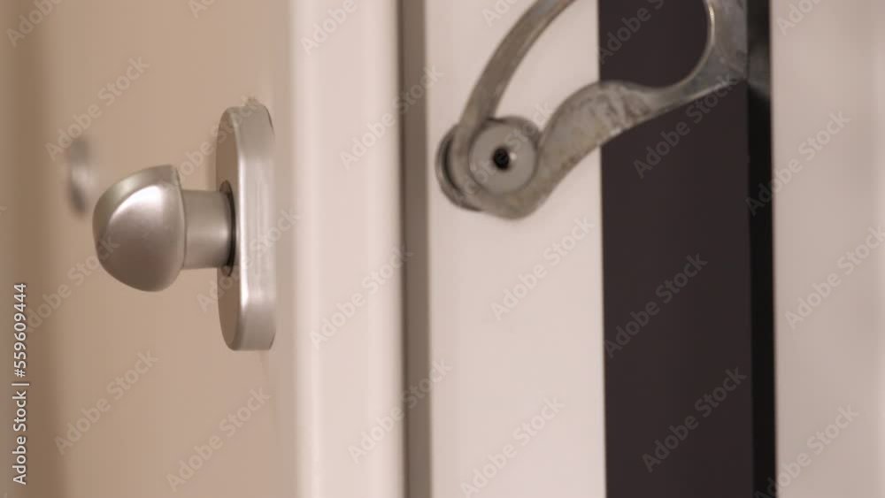 Male close the latch for the white door. A man try to protect the house with a latch indoor. Male close the latch for the white door. A man try to protect the house with a latch indoor.
