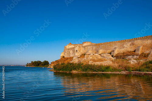Old stone fortress on the shore of the lake. Beautiful sunny landscape with fortress and blue sky