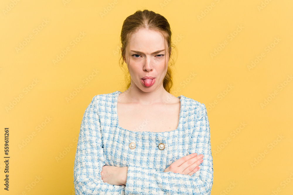 Young caucasian redhead woman isolated on yellow background funny and friendly sticking out tongue. Young caucasian redhead woman isolated on yellow background funny and friendly sticking out tongue.